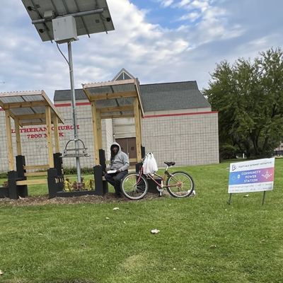 A person sitting on a bench at once of BLVD Harambee's community power stations