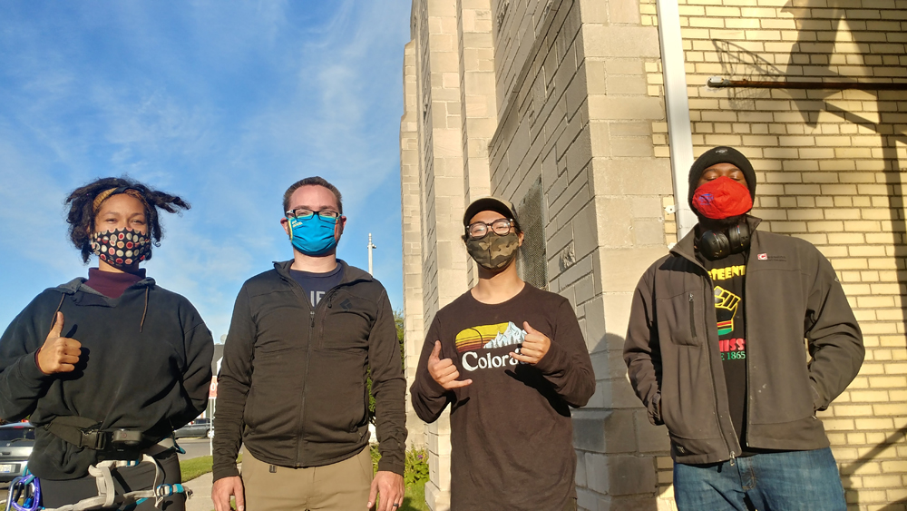4 digital stewards posing in front of a brick building, wearing masks and long sleeves
